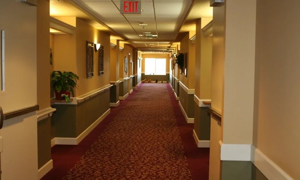 A well-lit hallway with a patterned carpet and wall sconces.