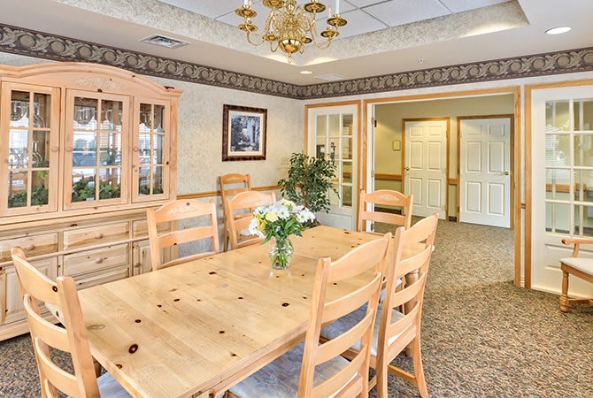 A cozy dining room with wooden furniture and a chandelier, adorned with a vase of flowers.
