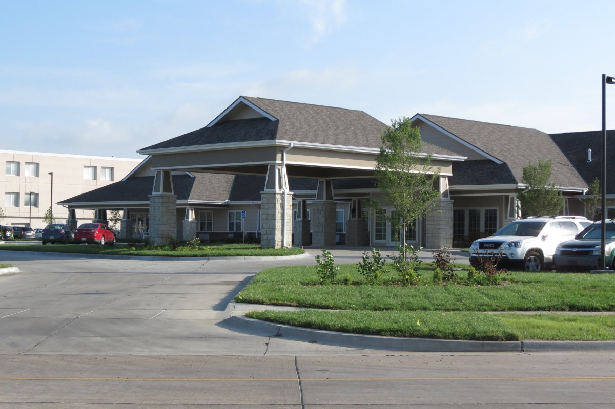 A modern office building with a driveway and parked cars.