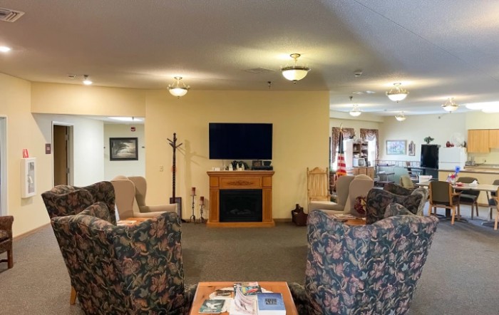 A cozy living room with a seating area facing a television and fireplace.