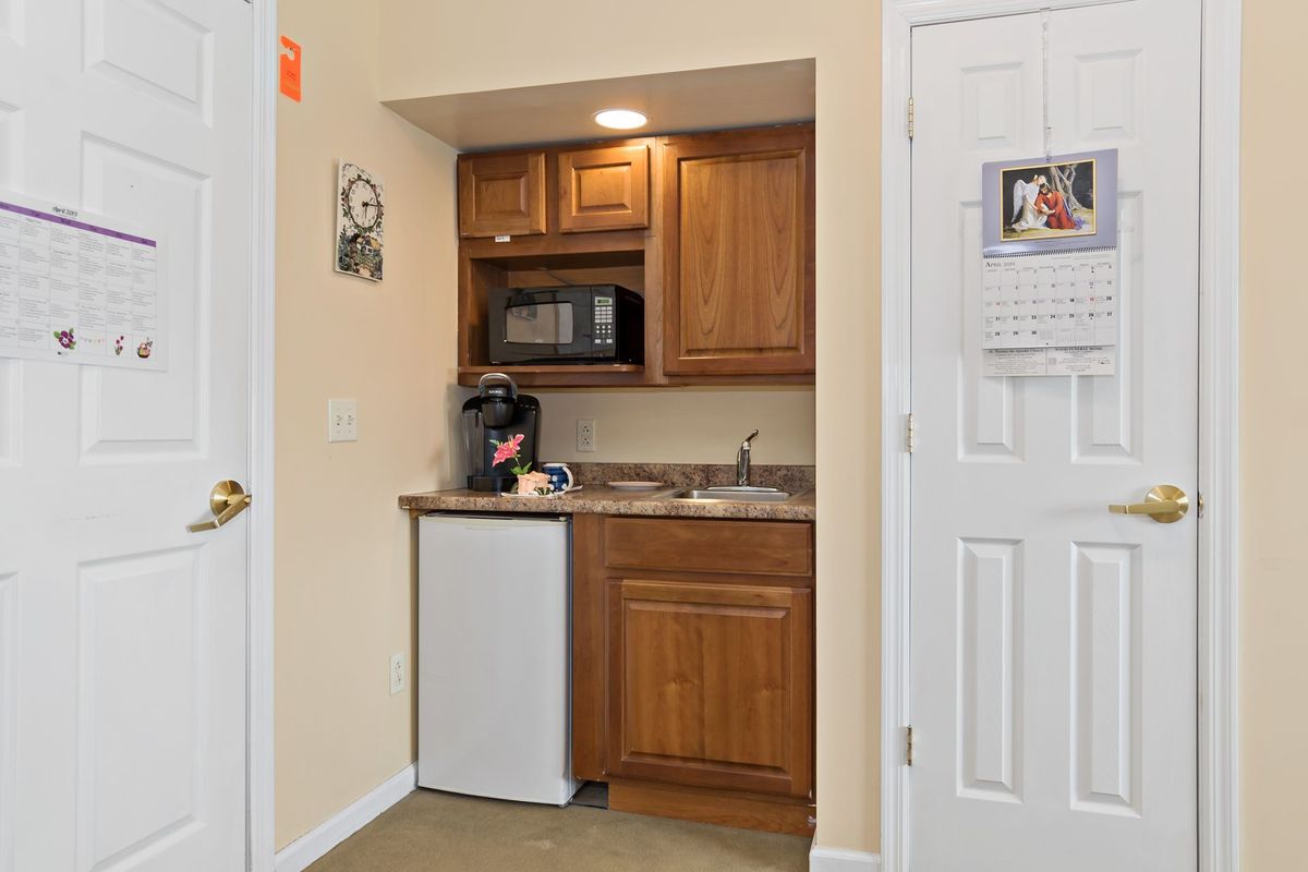 A compact kitchenette with a microwave, mini fridge, sink, and coffee maker.