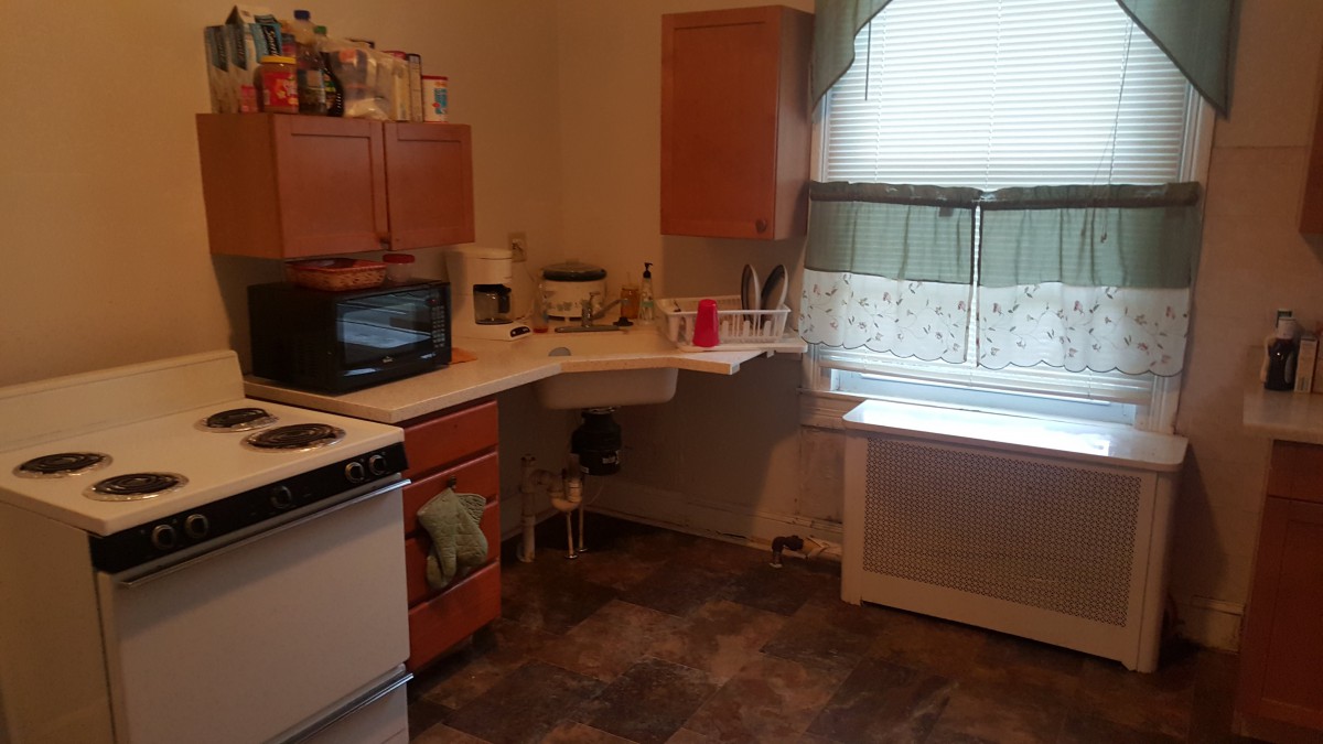 A cozy kitchen with wooden cabinets, a stove, and a microwave on the countertop.