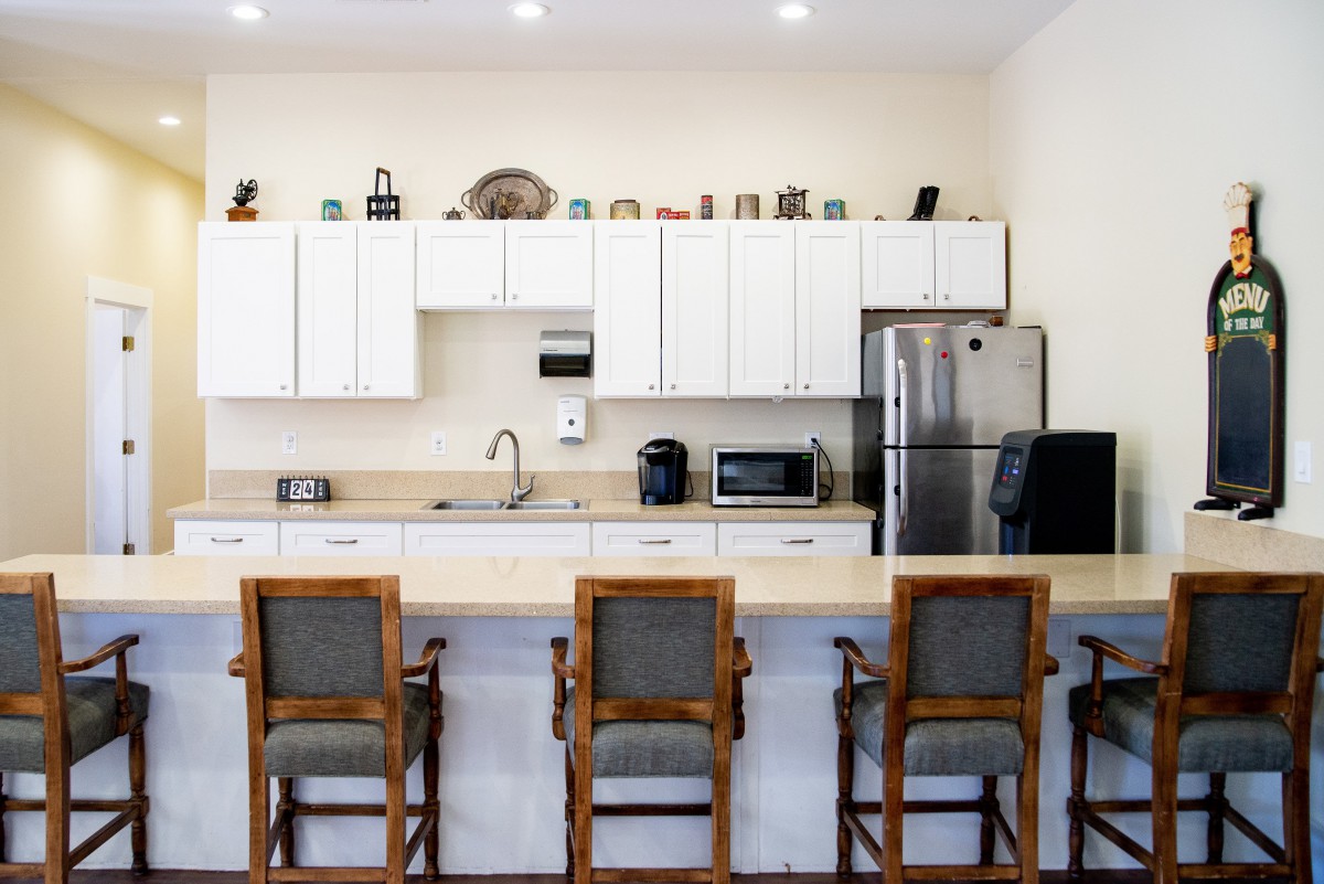 A modern kitchen with a clean countertop and high chairs, featuring sleek white cabinets and stainless steel appliances.