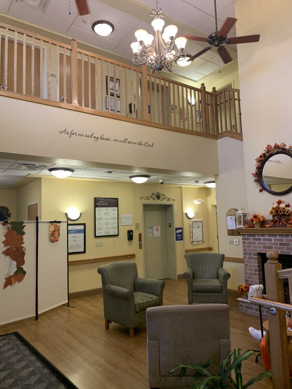A cozy lobby area with autumn-themed decorations, featuring a seating area, fireplace, and chandelier.