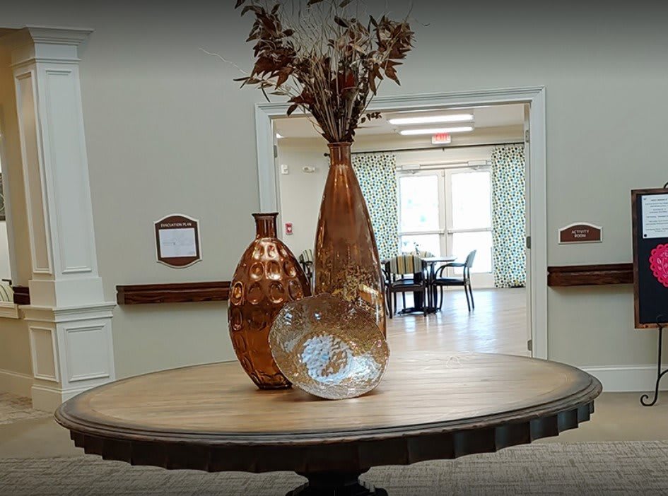 A decorative arrangement of vases with dried flowers on a round table in a room.