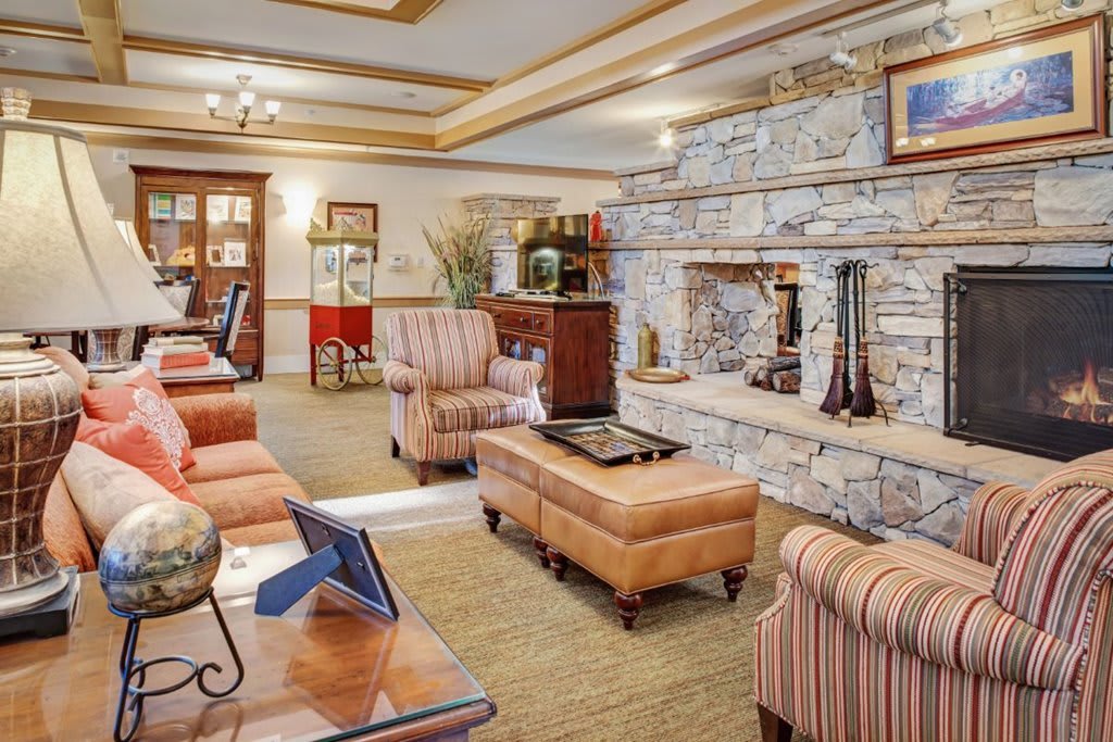 A cozy living room with a stone fireplace, comfortable seating, and warm decor.