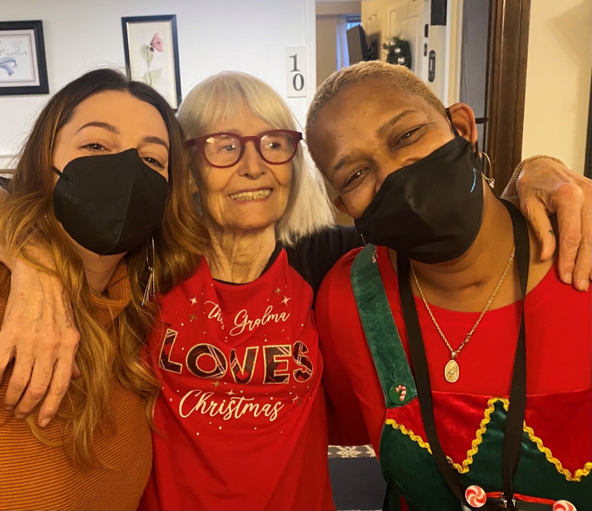 Three people wearing festive clothing and masks share a joyful moment together.