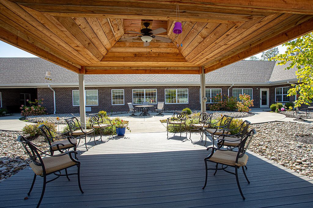 A cozy outdoor patio with a wooden gazebo and seating arrangement overlooking a garden.