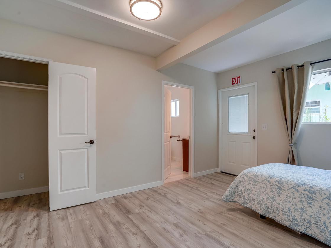 A minimalist bedroom interior with wooden flooring and natural light.