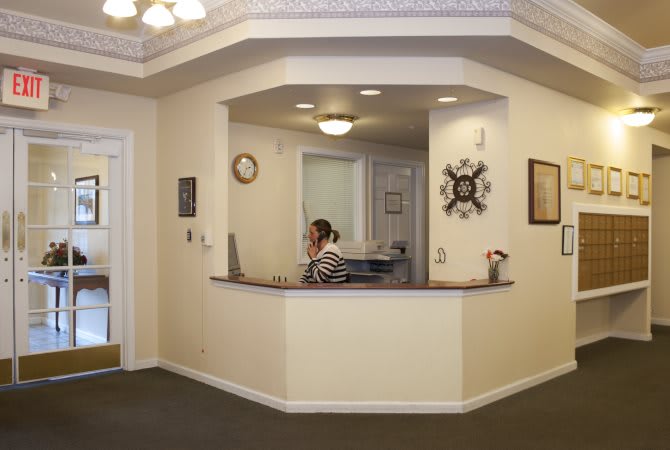 A receptionist at a desk in an office setting, answering the phone.