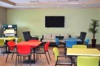 A colorful meeting or break room with various chairs and tables, featuring a television on the wall.