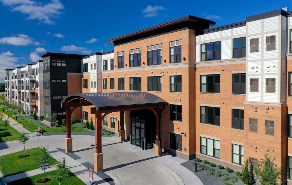 A modern brick building with a prominent arched entrance under a clear blue sky.
