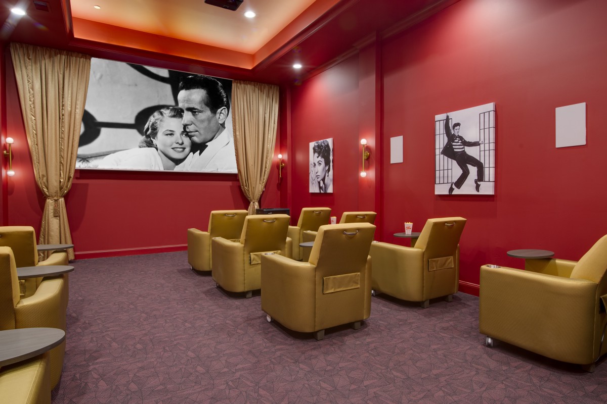 A cozy home theater with red walls, featuring comfortable armchairs and classic movie posters.