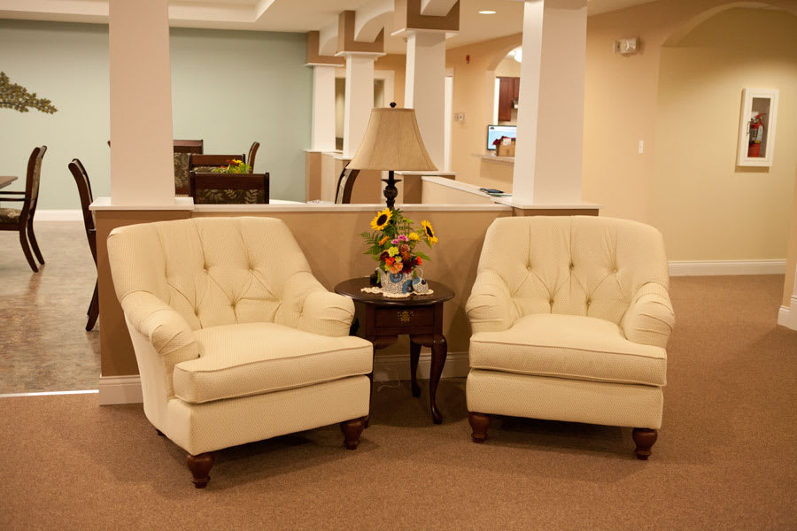 A cozy seating area with two upholstered chairs and a table with a lamp and flowers, creating a warm and inviting atmosphere.