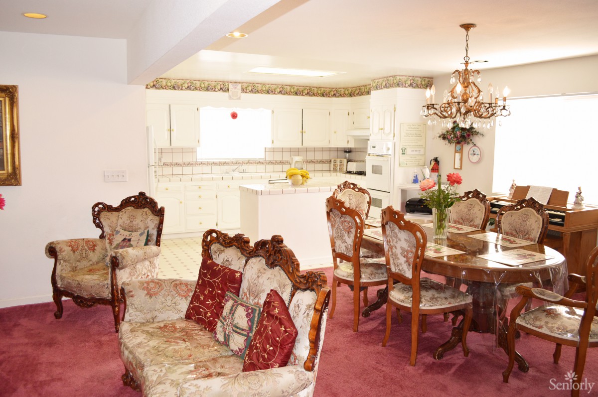 A vintage-style open-plan kitchen and living area with floral upholstered furniture and a chandelier.