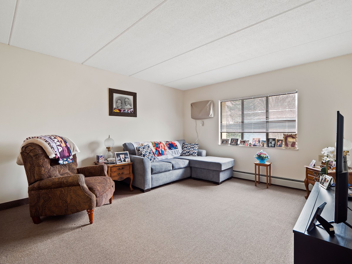 A cozy living room with a gray sectional sofa, armchair, and large window.