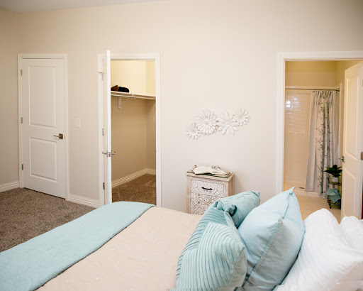 A serene and minimalist bedroom featuring a neatly made bed with pastel-colored pillows and two closet doors.