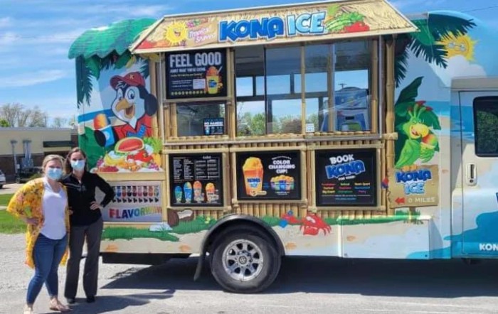 A vibrant Kona Ice food truck with tropical-themed decorations parked outdoors.