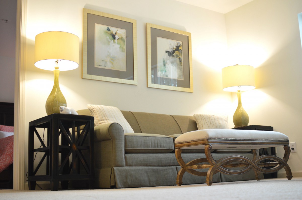 A cozy living room with a comfortable sofa, stylish lamps, and framed artwork.