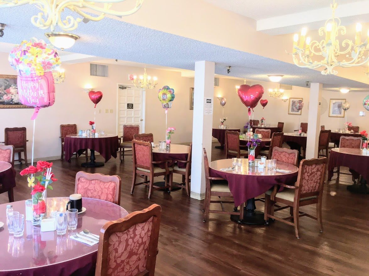 A decorated dining area with tables, chairs, and heart-shaped balloons.