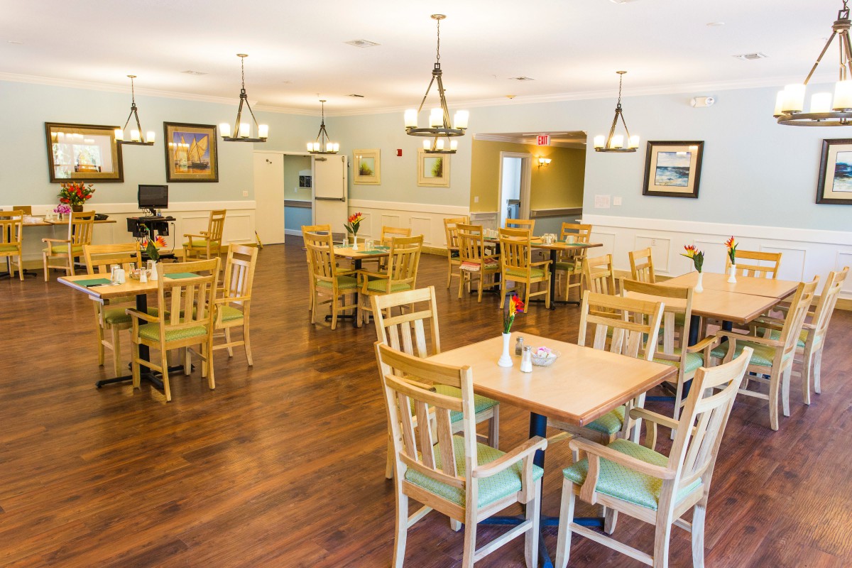 A spacious dining area with wooden tables and chairs, complemented by elegant chandeliers.