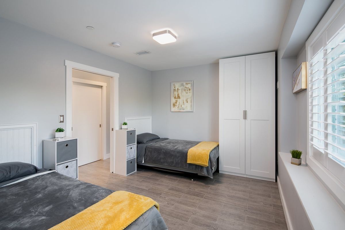 A modern bedroom with twin beds, featuring minimalist decor and a wardrobe.