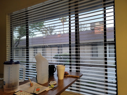 A view from inside a room showing blinds, a table with food and drinks, and an exterior scene.