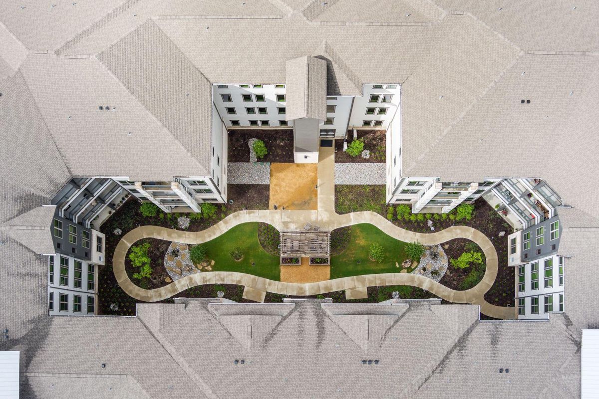Aerial view of a building complex with a landscaped garden and winding pathways.