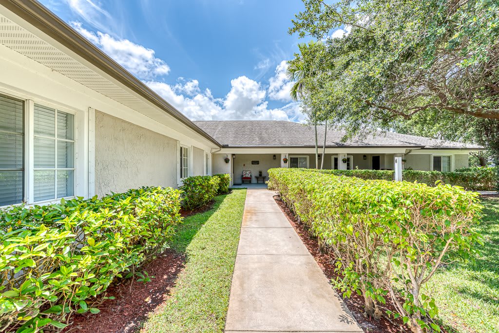 A charming residential home with a pathway lined by hedges leading to the entrance.