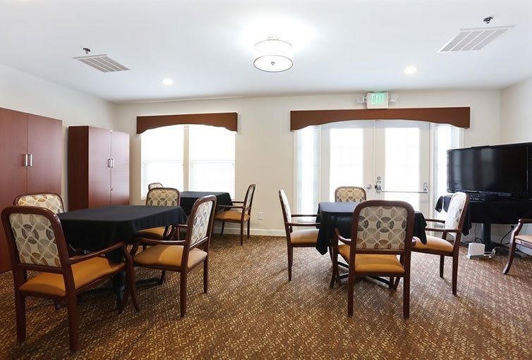 A well-lit dining area with tables and chairs arranged on a carpeted floor.