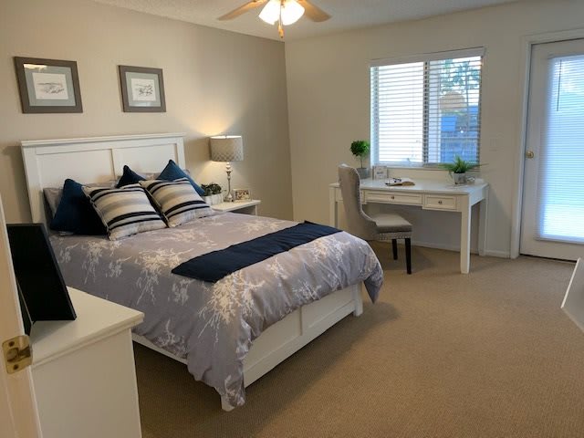 A cozy and well-decorated bedroom featuring a comfortable bed, desk, and soft lighting.