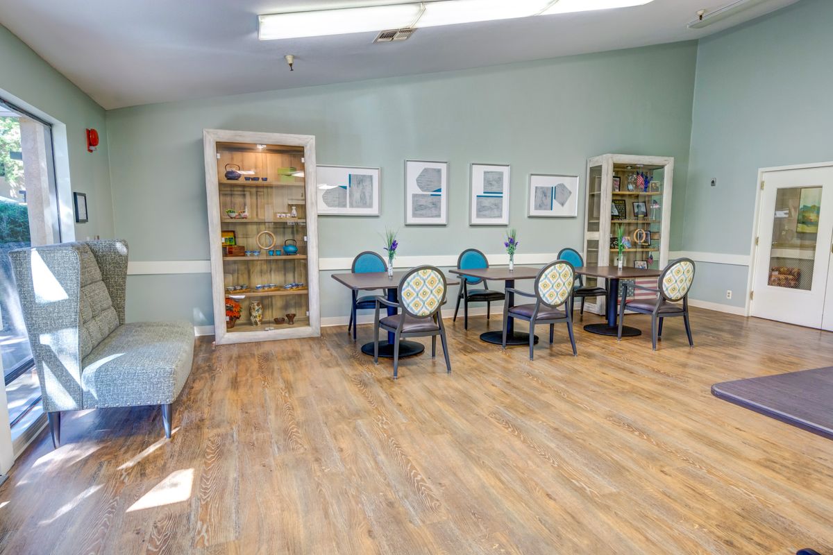 A room with tables, chairs, and bookshelves under soft lighting.