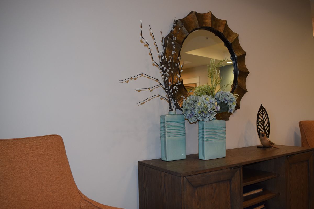 A modern interior setup featuring a decorative mirror, vases with flowers, and stylish furniture.