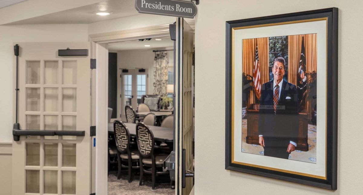 A view of an office conference room with a portrait and a sign reading 'Presidents Room'.