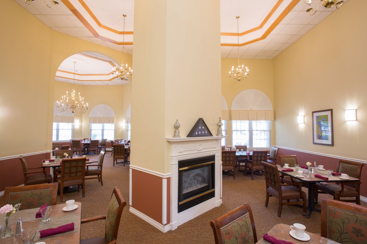 A spacious dining area with a central fireplace and elegant chandeliers.