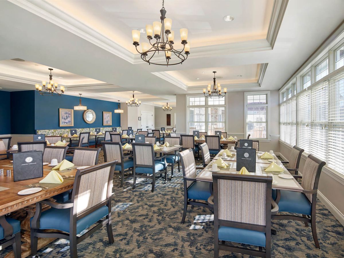 Elegant dining room with chandeliers and neatly arranged tables under natural light.