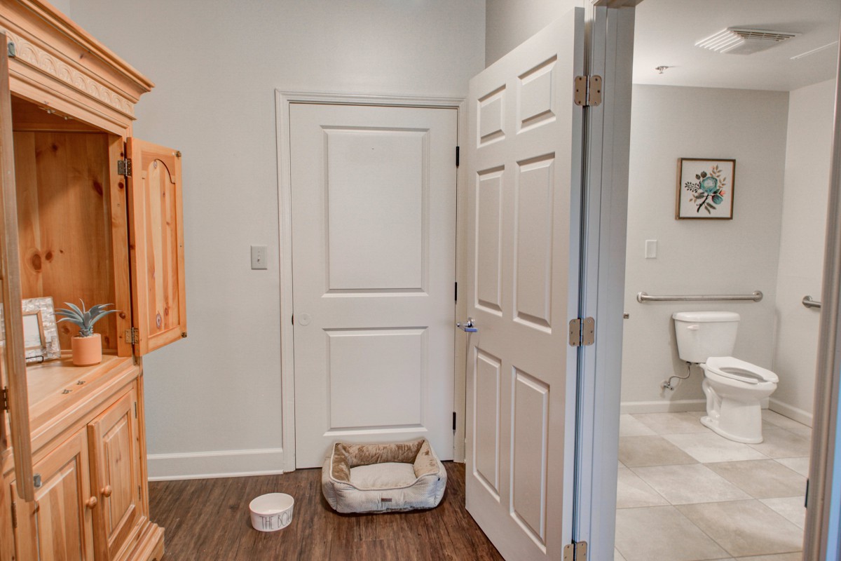 A cozy room corner with a pet bed and water bowl near a door.