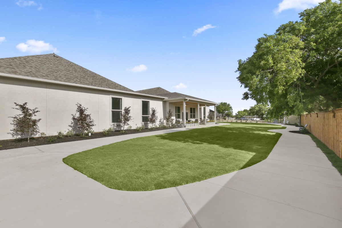 A suburban house with a well-maintained lawn and driveway under a clear blue sky.