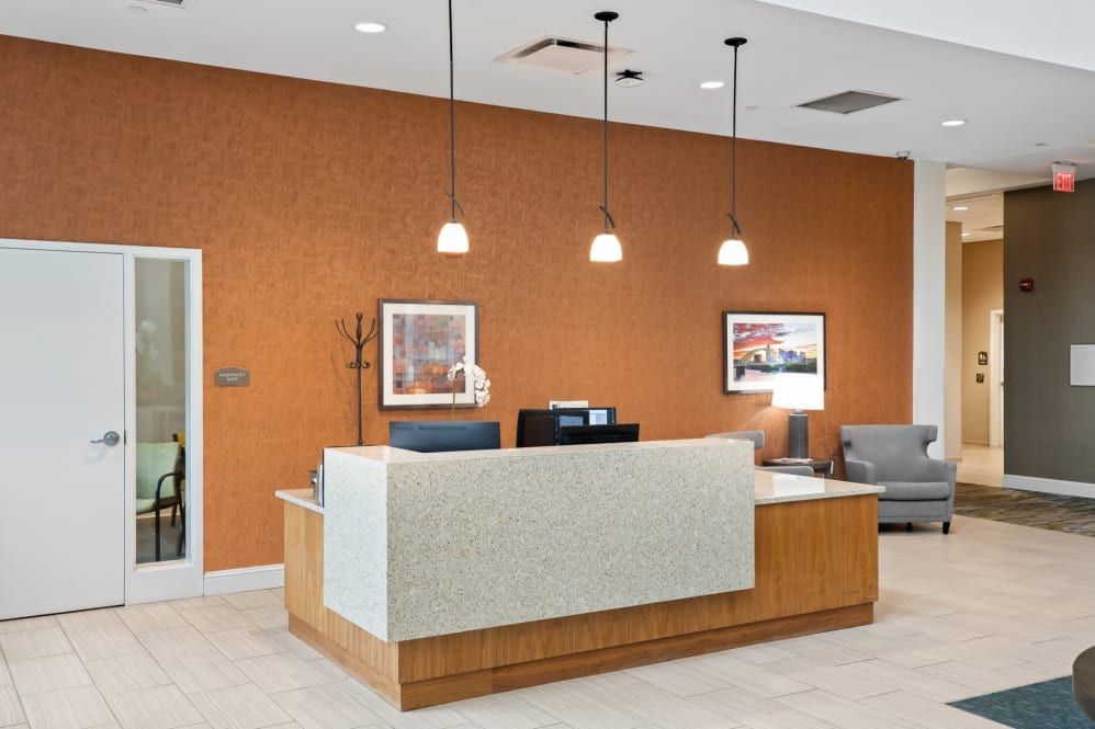 A modern office reception area with a front desk, seating, and decorative lighting.