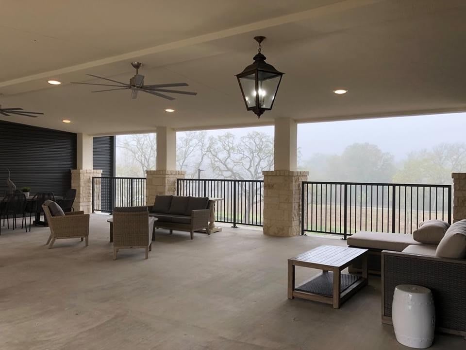 A spacious outdoor patio with comfortable seating and ceiling fans, offering a view of the surrounding landscape.