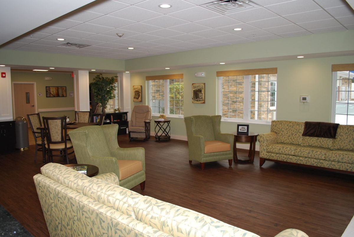 A comfortable seating area with armchairs, sofas, and large windows in a living room setting.