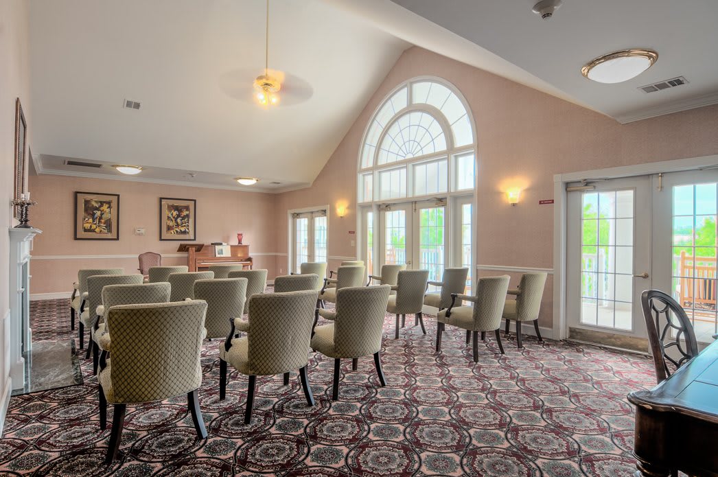 A well-lit conference room with a patterned carpet and rows of chairs facing the front.