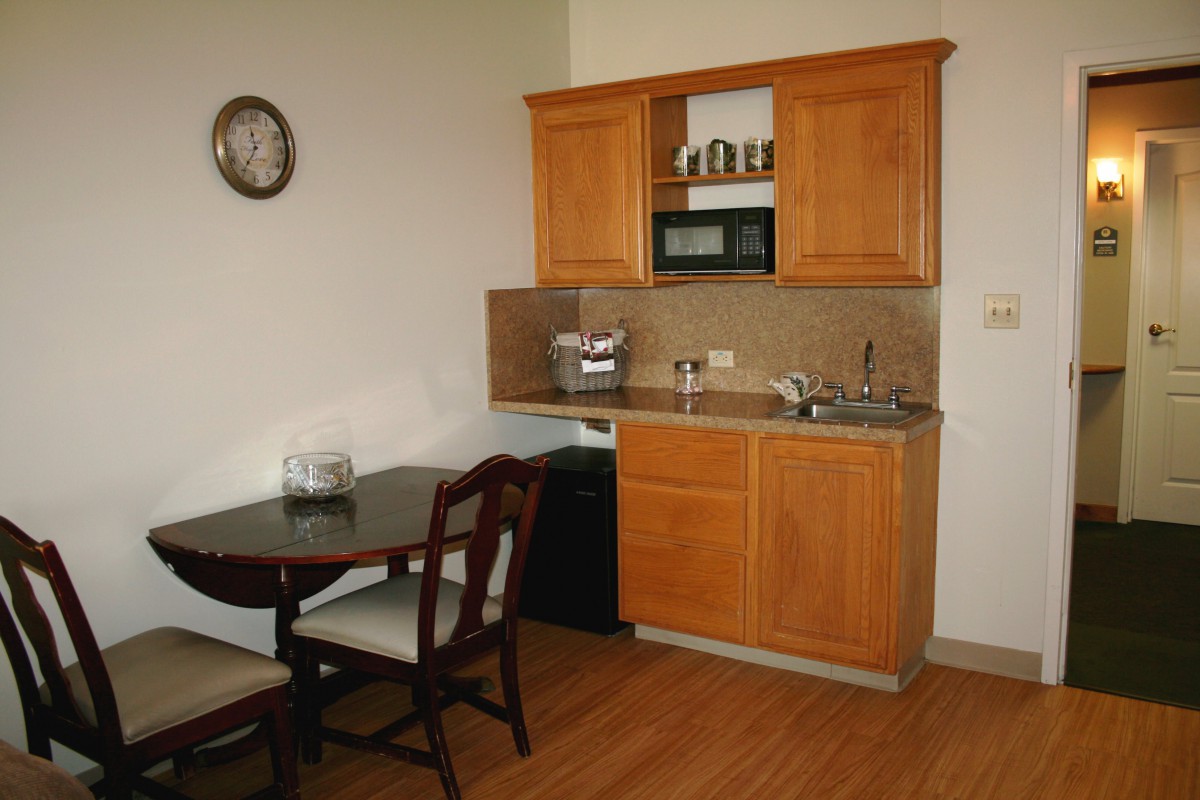 A small kitchenette with wooden cabinets, a microwave, and an adjacent dining area.