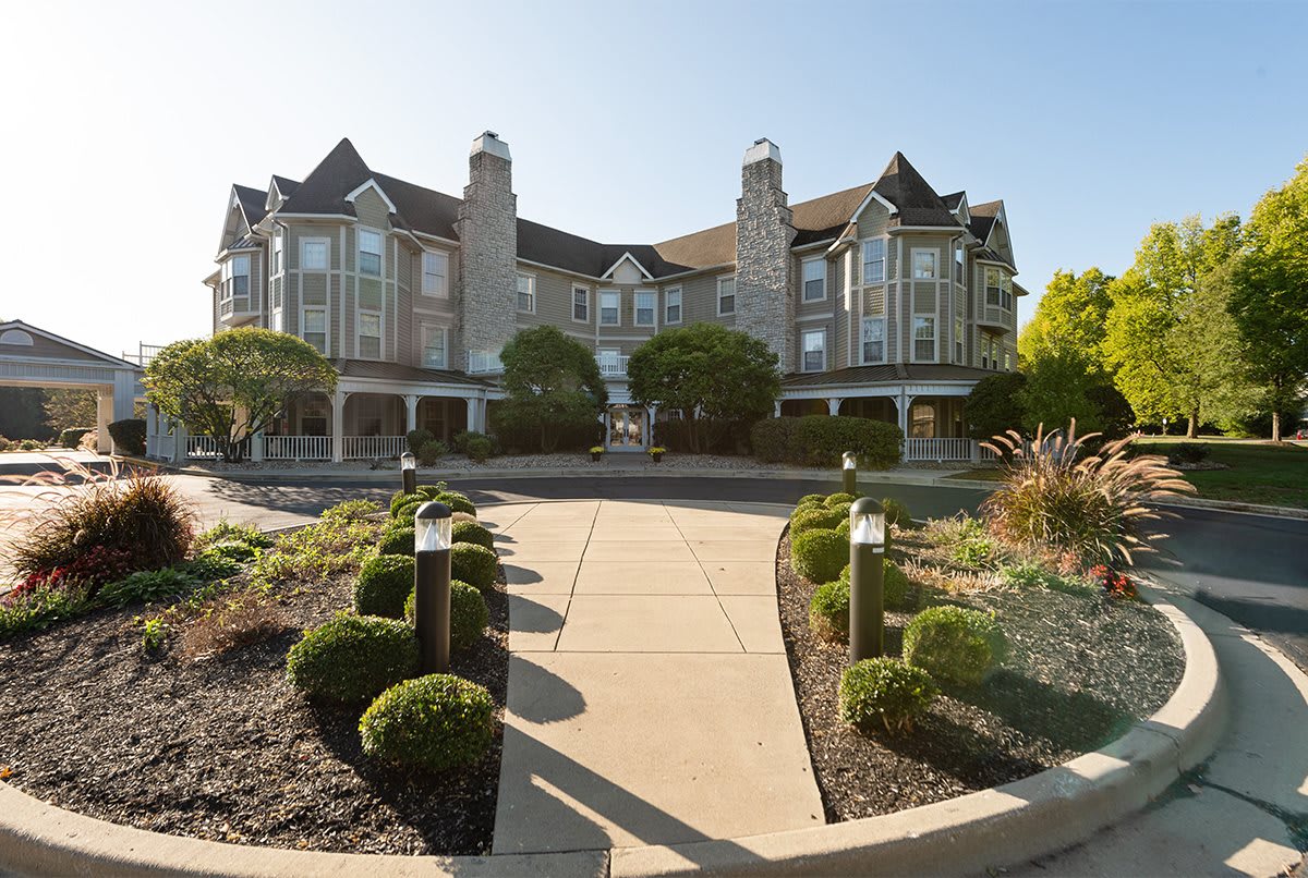 A grand hotel with classic architecture, surrounded by well-maintained gardens and a paved pathway.