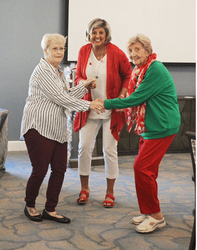 Three seniors enjoying a lively dance together indoors.