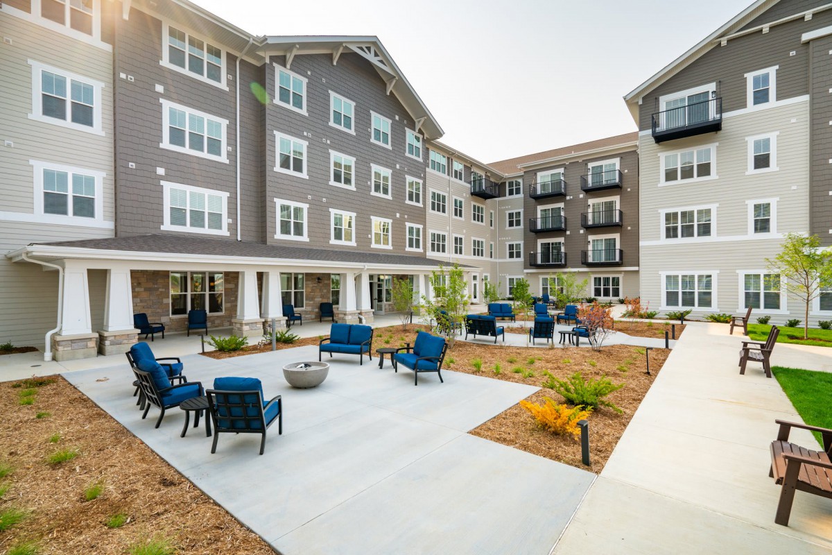 A modern apartment building featuring a spacious courtyard with outdoor seating and landscaped areas.