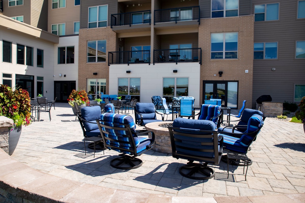 Outdoor seating area with blue-cushioned chairs at a modern apartment complex.