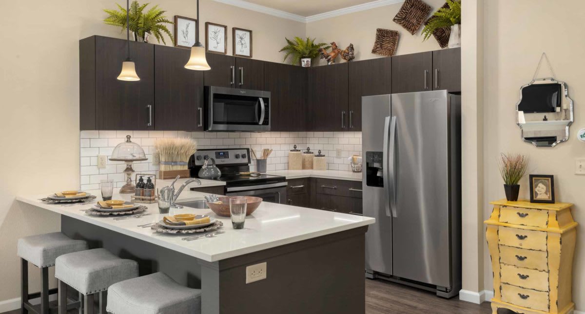 A modern kitchen with dark cabinets, stainless steel appliances, and a central island.
