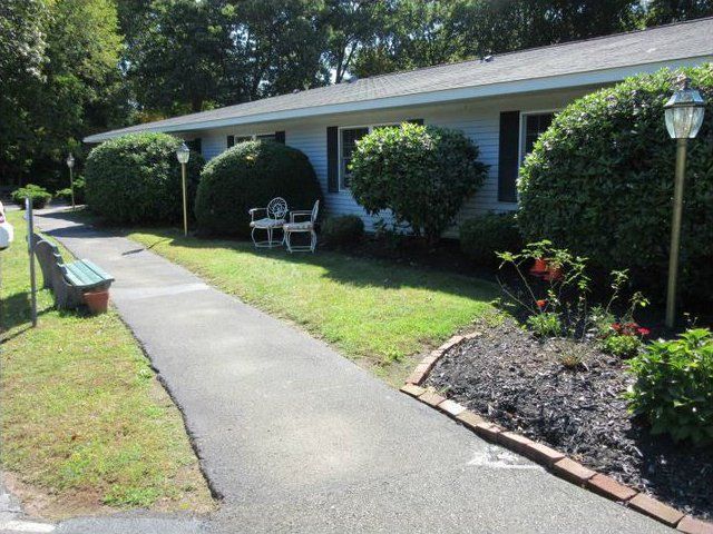 A well-maintained front yard with a pathway and neatly trimmed bushes.