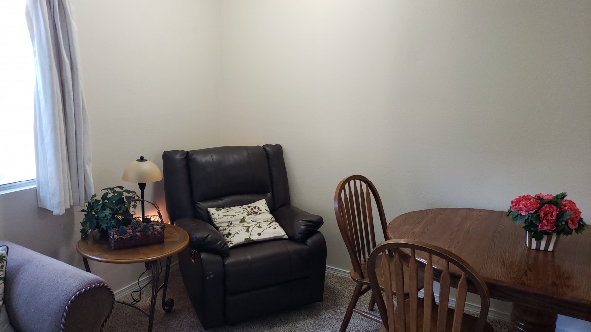 A cozy corner with a recliner, side table, and dining set.